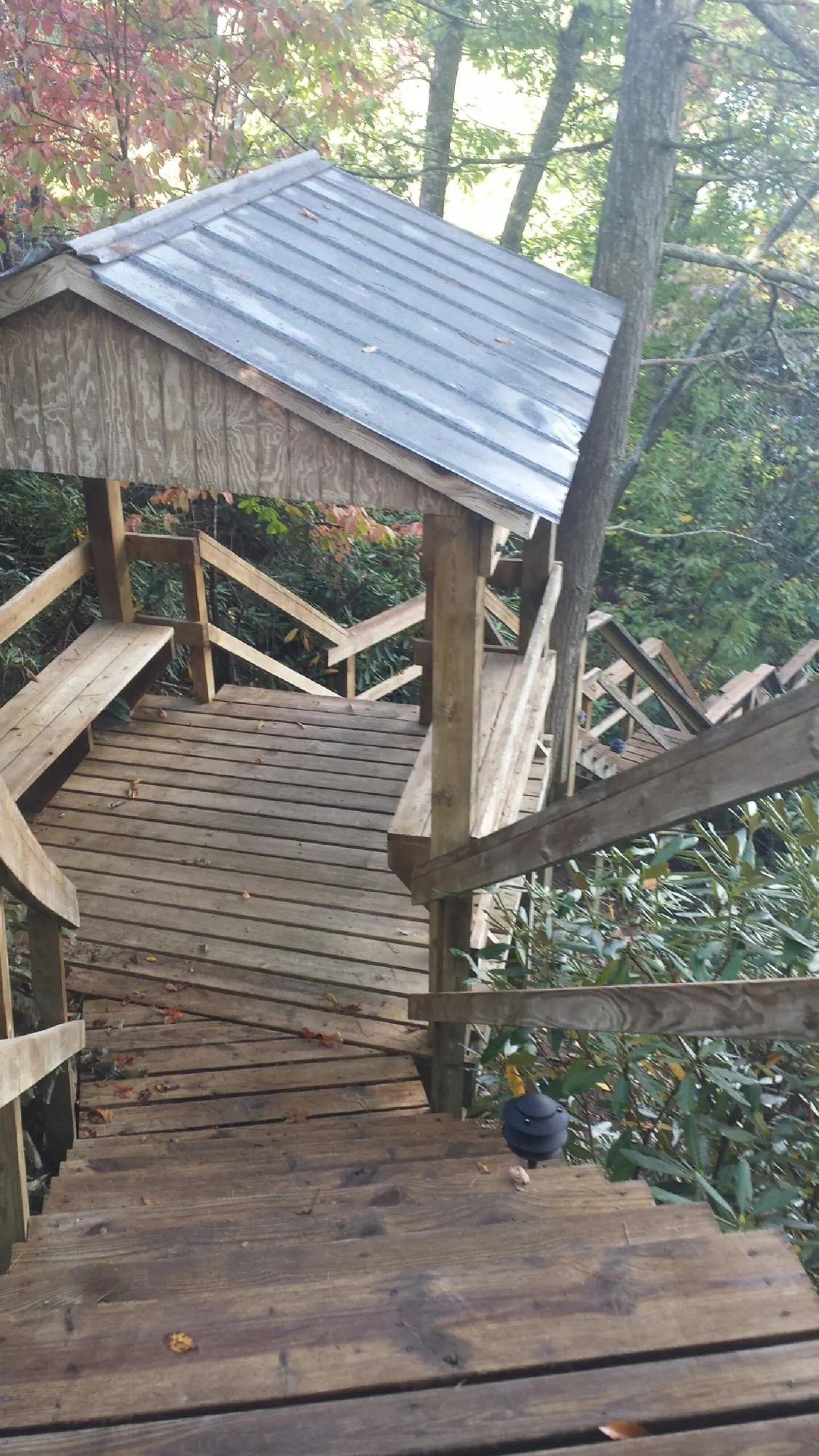 Metal roofed shelter over wooden steps on a wooded walkway — Skylight Repair & Installation work by our crew in Angola