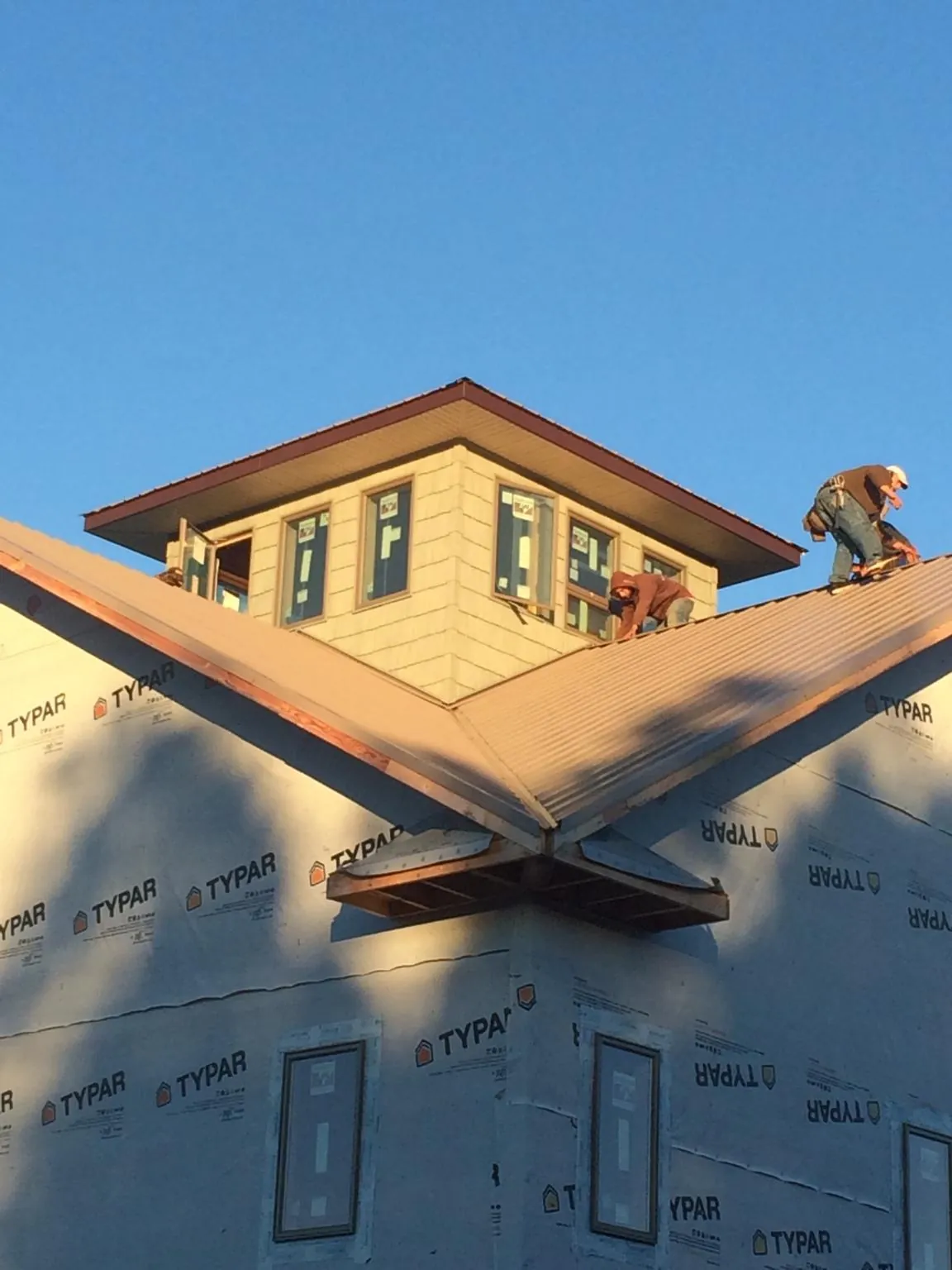 Roofers working around a rooftop cupola on a new metal roof at sunset — Roof Waterproofing in Angola by Roofing Brothers